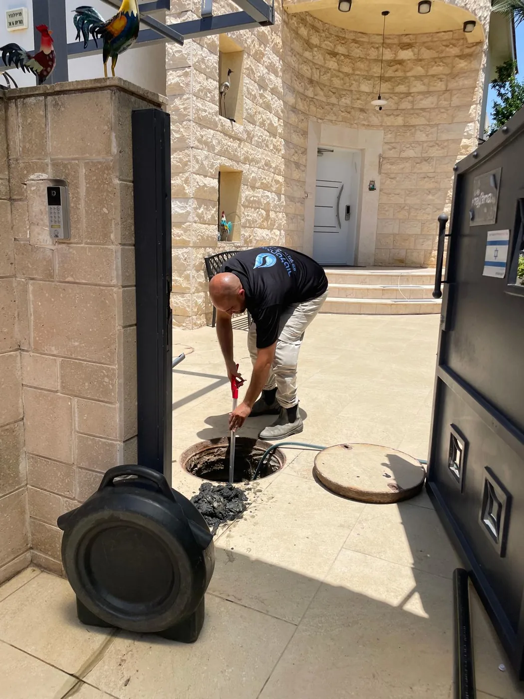 יצחק האינסטלטור עם ציוד פתיחת סתימות בכניסה לבית בנס ציונה לטיפול בסתימת מגבונים בשוחת הביוב