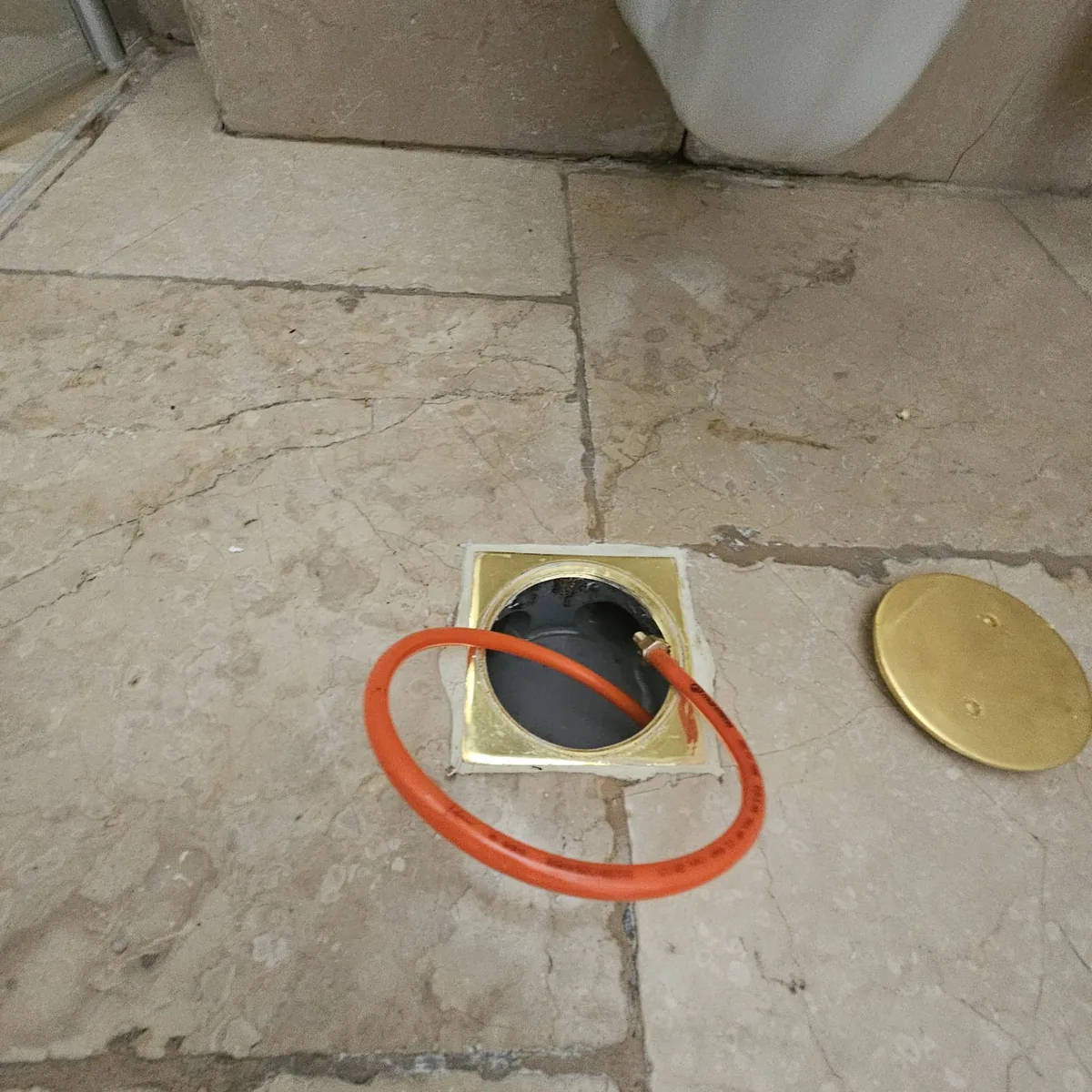 פתיחת פתח ניקוז ברצפה באיתור נזילה באשדוד - הסרת כיסוי פליז וגישה לצנרת