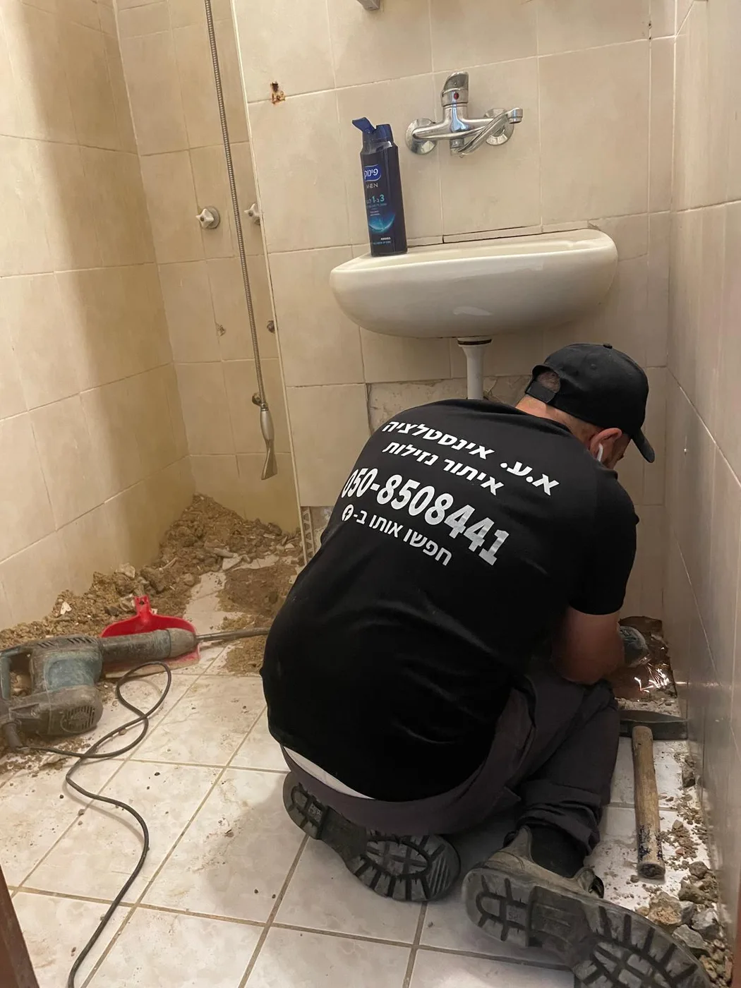 יצחק עקרי בעבודת אינסטלציה מתחת לכיור