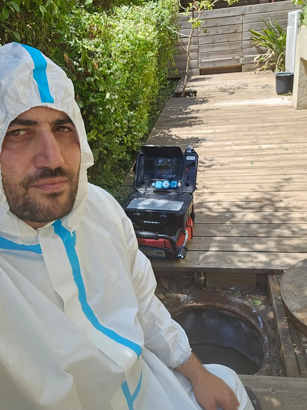 יצחק עקרי ליד שוחת ביוב עם מצלמת צנרת